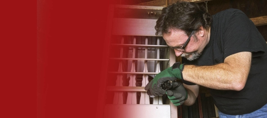 A technician wearing protective gloves is servicing a furnace