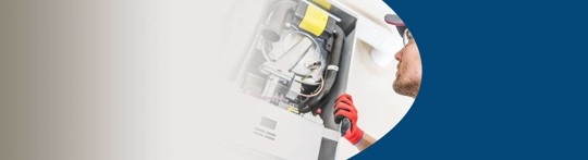 Close up image of a technician servicing an air conditioning unit.