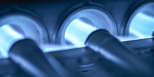 Close-up of a gas furnace with blue flames.